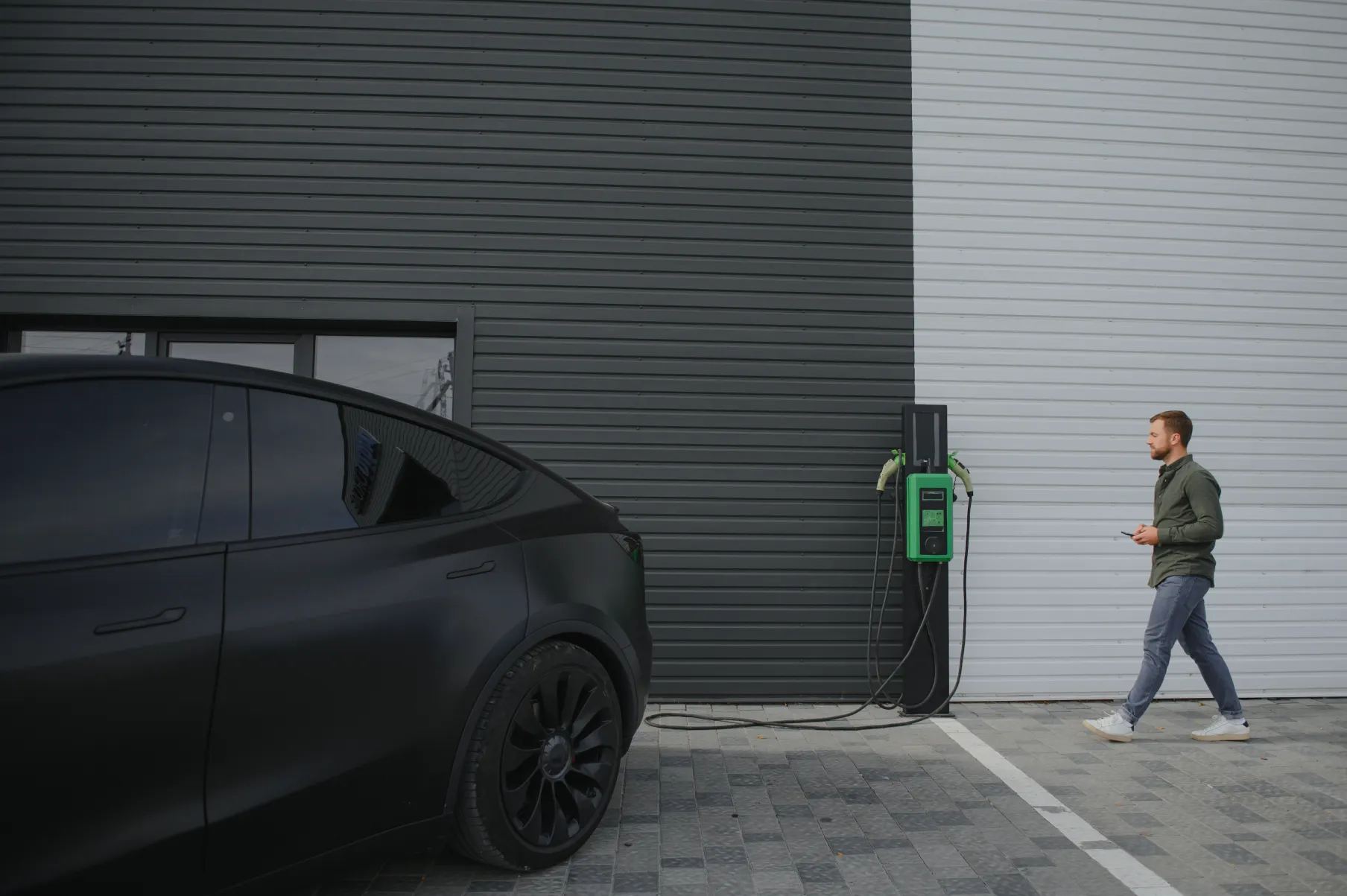 Man walking with phone to parked Tesla Model X